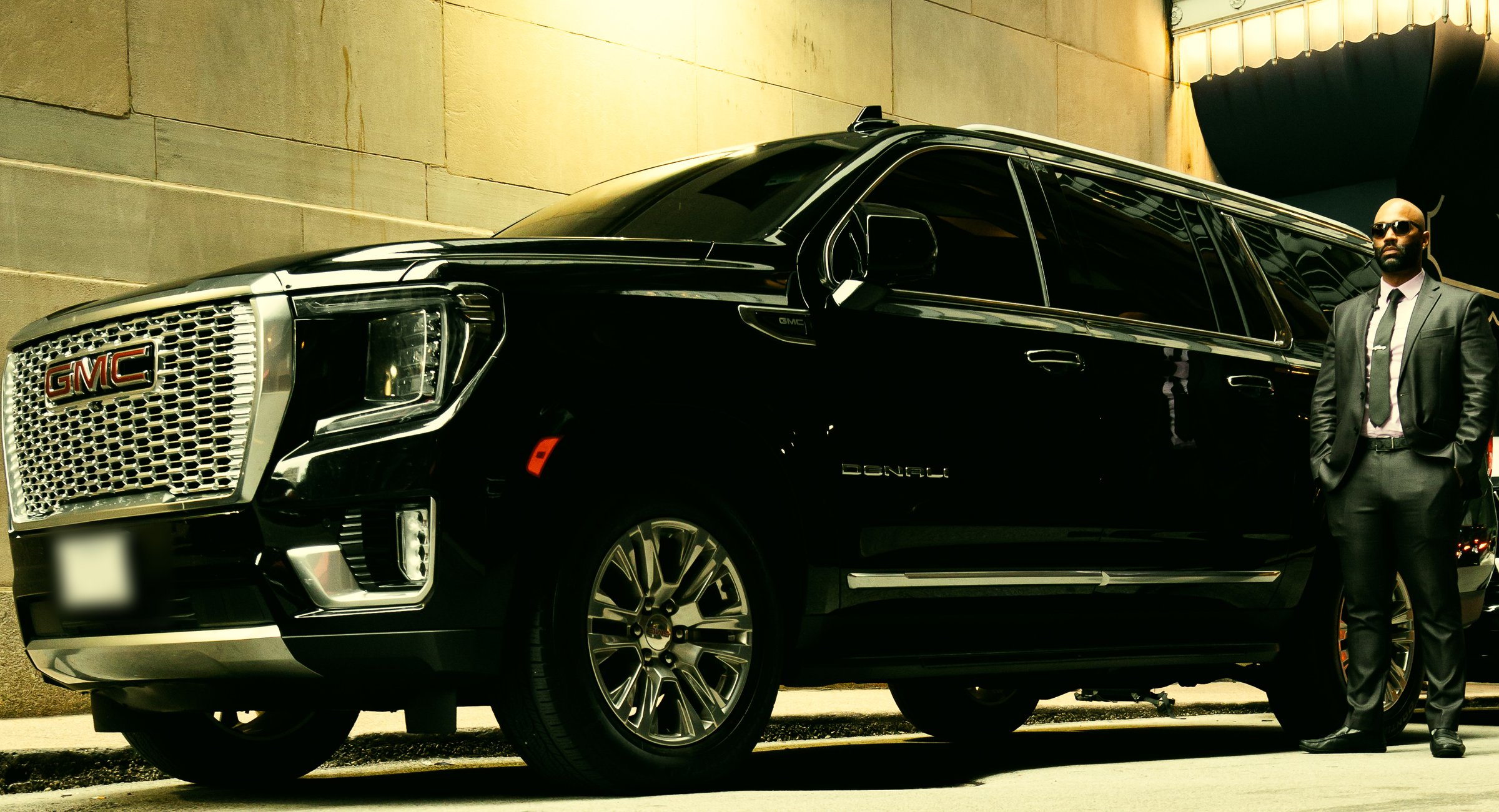 Nigel standing at the rear door of the black GMC Yukon Denali XL