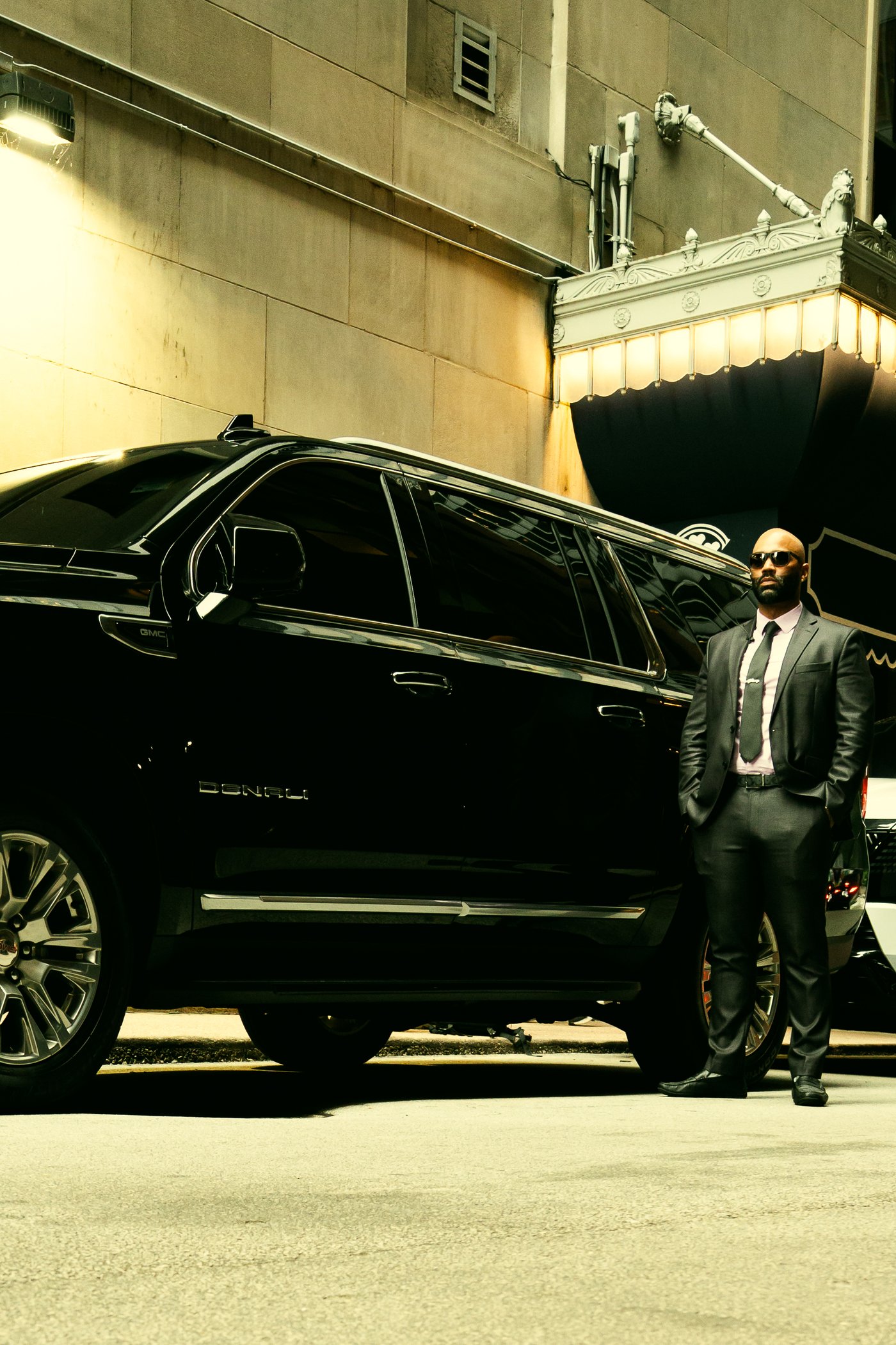 Nigel at the open rear door of the black GMC Yukon Denali XL — executive SUV